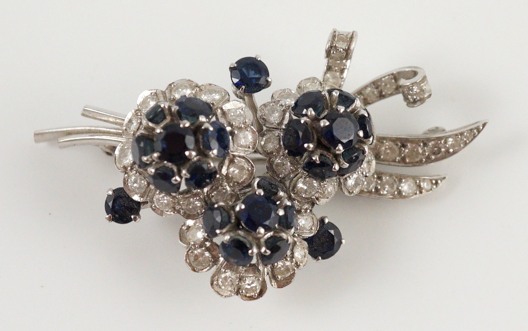 A white gold, sapphire and diamond cluster set floral spray brooch